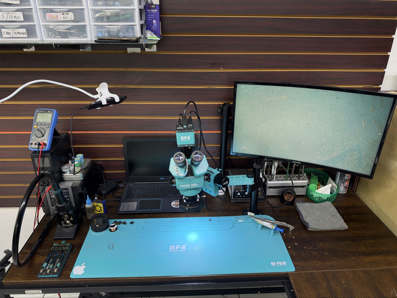 The repair workbench at Game Over: a microscope, soldering station, laptop and monitor used for board-level console repairs